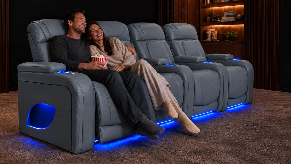 A couple relaxing in tan leather home theater recliners with blue base lighting